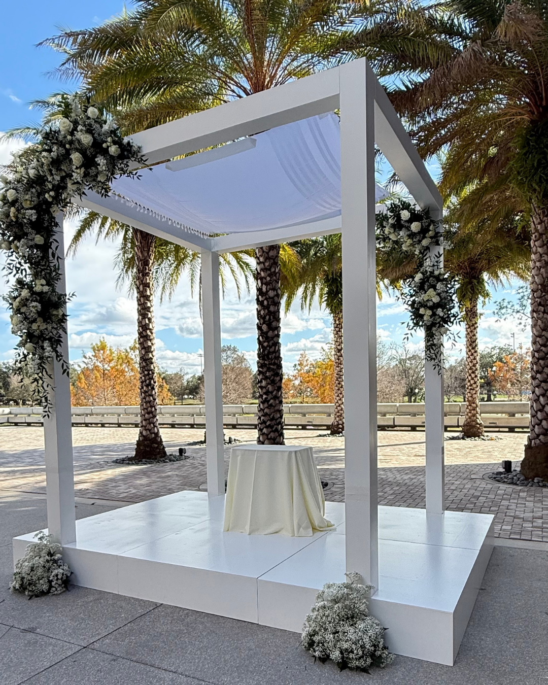 Custom floral statement arch and elevated stage installation created for a luxury event, featuring bespoke fabrication and architectural design in Orlando.